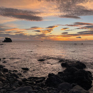 Apricot and grey mottled clouds above a darkened sea.