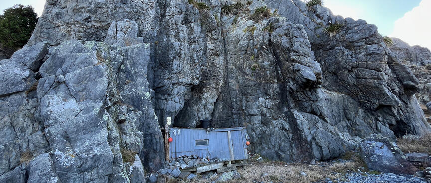 A rectangular wooden wall at the foot of a rockface. 