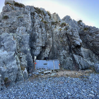 A rectangular wooden wall at the foot of a rockface. 
