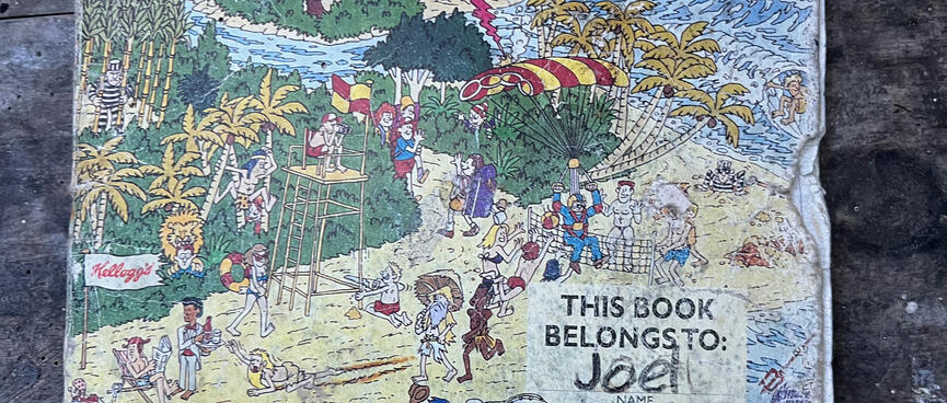 The cover of a 1B5 exercise book features a whacky illustration of a UFO attacking a beach scene.