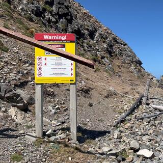 A warning sign on a pebbly beach.