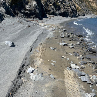 Tyre prints in the sand right next to the waterline.
