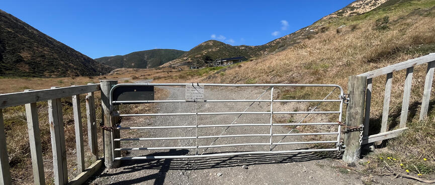 A metal gate with a small handwritten sign on it.