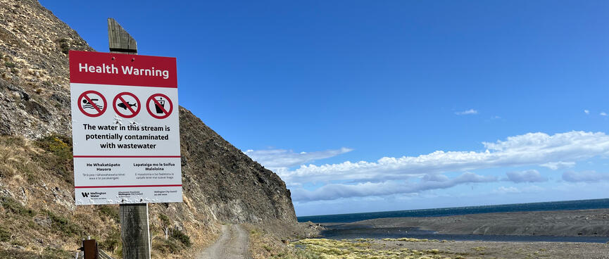 A ʼHealth Warningʼ sign on the side of a coastal trail.