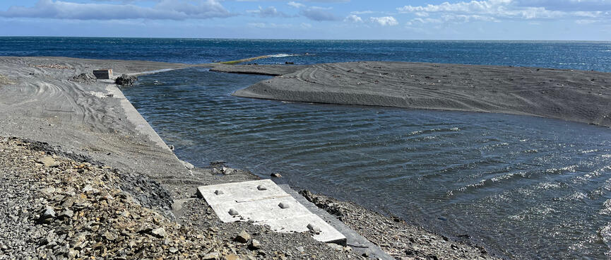Water flows down a manmade channel towards the sea.