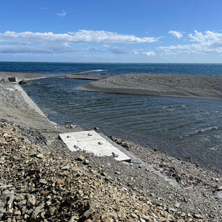 Water flows down a manmade channel towards the sea.