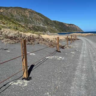 Iron fence posts and taut wire on the side of the coastal road.