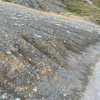 Finger shapes at the bottom of a dirt and shingle slope.
