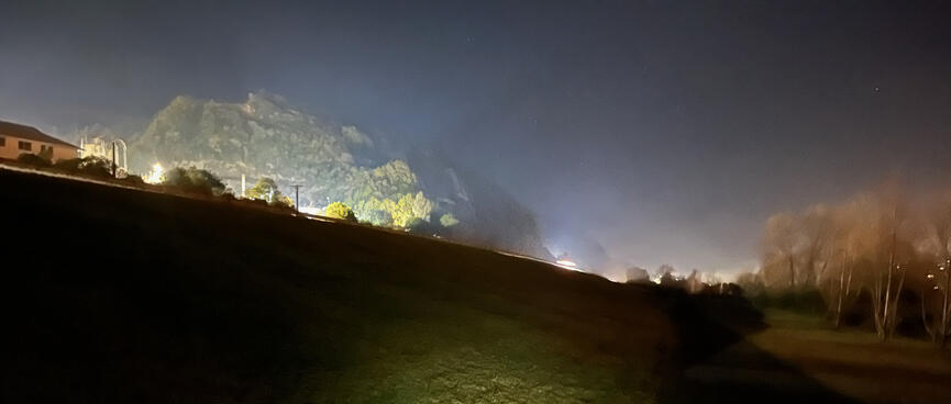 A scrub-covered hill is illuminated with flood lights.