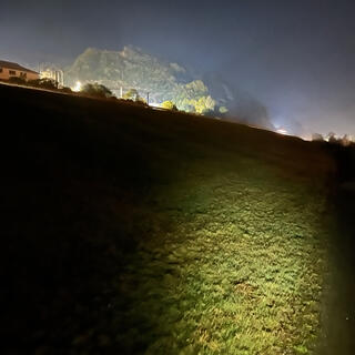 A scrub-covered hill is illuminated with flood lights.