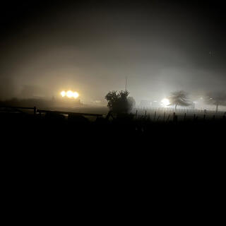 Floodlights create halos in thick mist.
