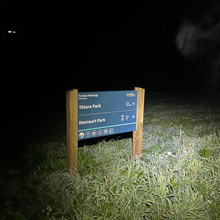 A blue and white sign pointing to Tõtara Park and Harcourt Park.