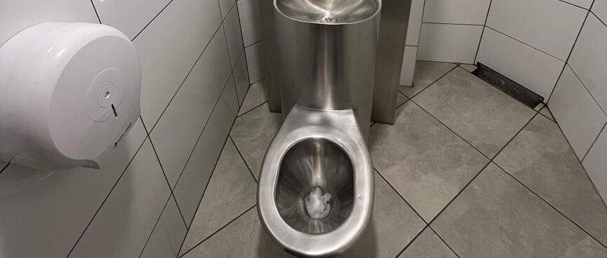 A meta toilet with a built-in sink, in a small tiled room.