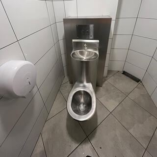 A meta toilet with a built-in sink, in a small tiled room.