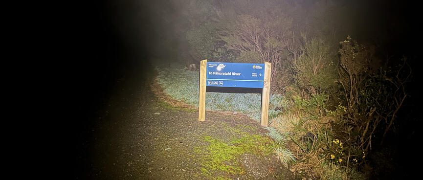A blue and white sign pointing to Pākuratahi River.
