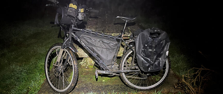My touring bike leans against a picnic table.