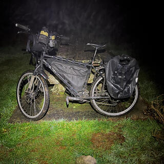 My touring bike leans against a picnic table.