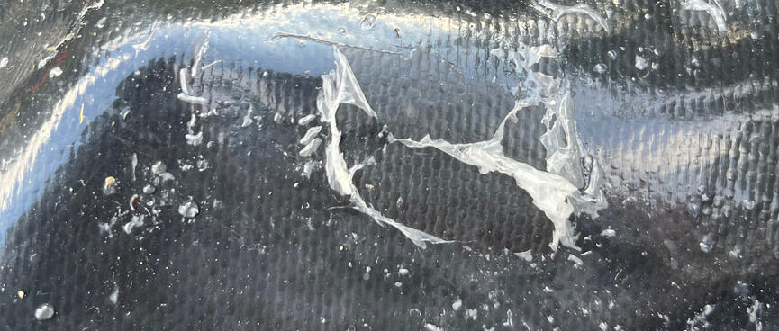 Shreds of white silicon on the shiny exterior of an Ortlieb pannier bag.