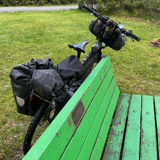 A green park bench with a small metal plaque.