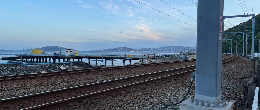 A jetty extends out from the coastline near railway tracks.