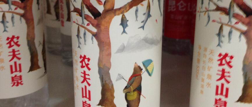 A bear with a fishing net gazes up at a tree of fish, on a water bottle label.