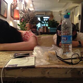Two young girls sleep on my table, by resting their heads on their arms.