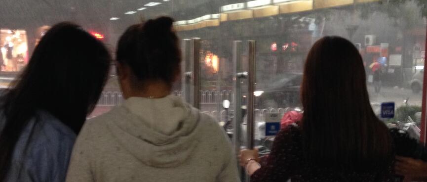 Young female shoppers stand inside the shop doors.