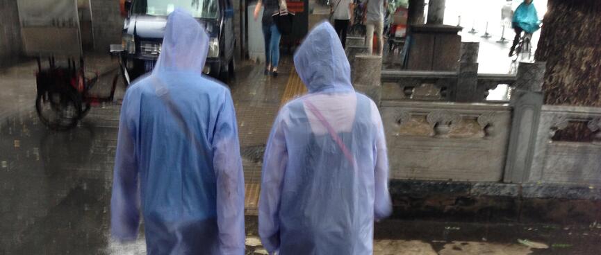Two people wear see through raincoats to beat the downpour.