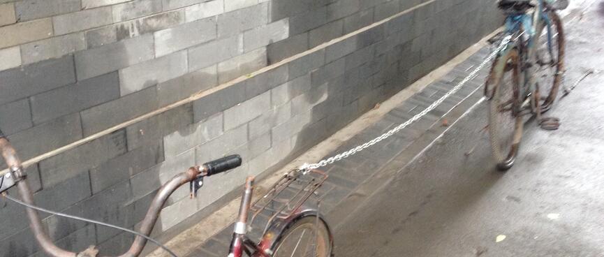 Two bikes are locked together with a long chain.
