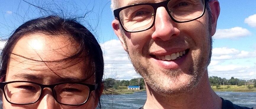 The wind whips Mandyʼs hair as we pose by the lake.
