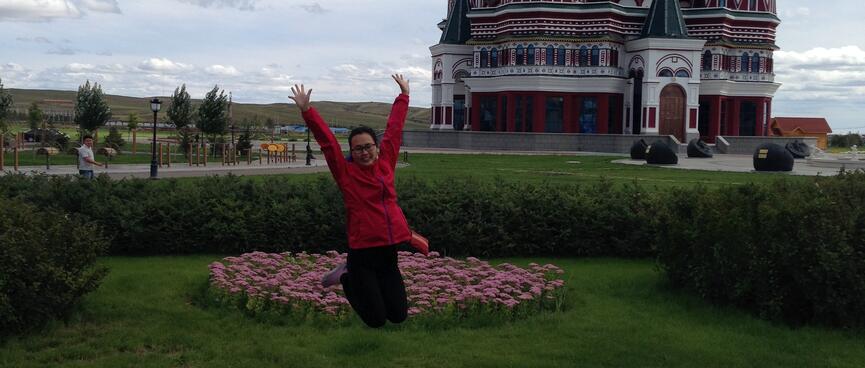 Mandy launches herself into the air, in front of a church with onion shaped domes.