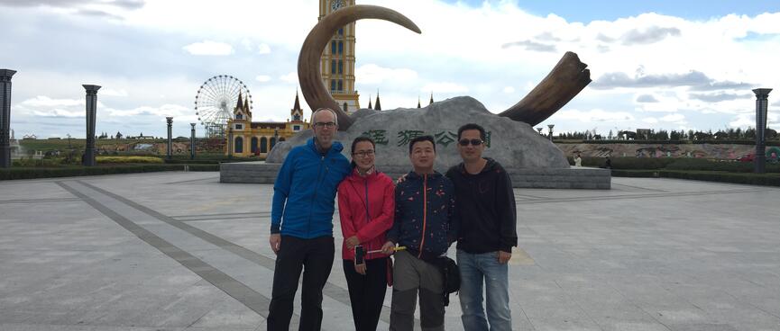Our group of four poses in front of a mammoth tusk set in concrete.