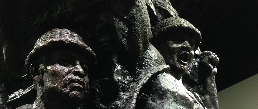 Metal statues depict bare chested miners wearing helmets.
