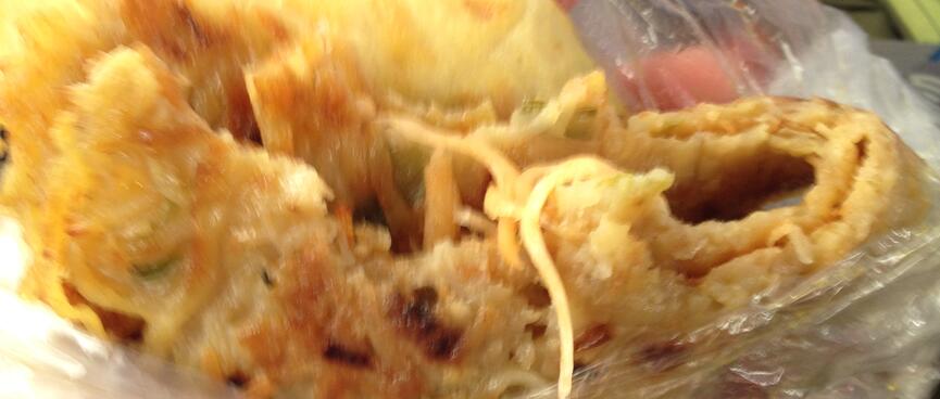 Noodles spill out of a thin wrap that has been rolled several times.