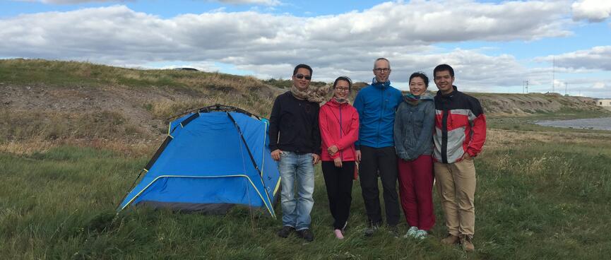 Five people stand next to a tent.