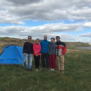 Five people stand next to a tent.