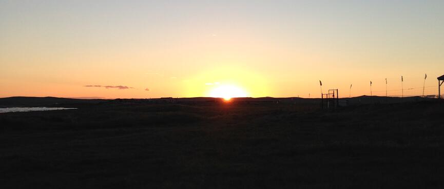 The bright sun is perched on the horizon.