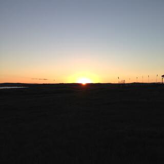 The bright sun is perched on the horizon.