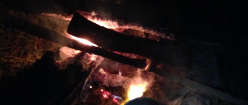A billy sits on top of a roaring fire.
