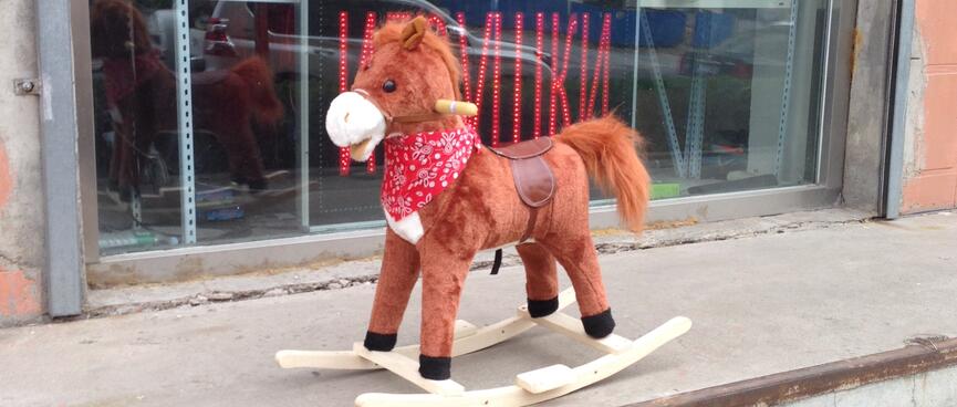 A brown rocking horse wears a red cowboy scarf.