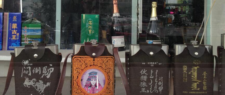 Hip flasks form a line in a shop window.