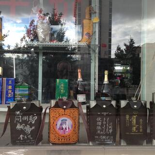 Hip flasks form a line in a shop window.