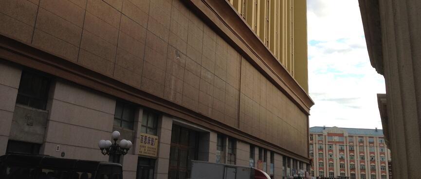 Cars and trucks line an alleyway between two large ornate buildings.