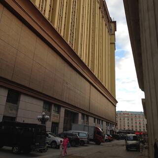 Cars and trucks line an alleyway between two large ornate buildings.