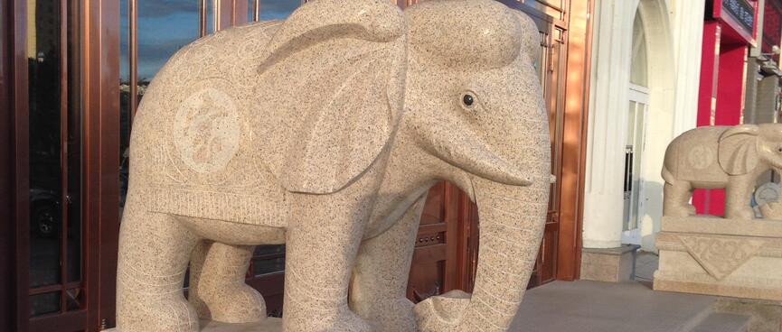 Stone elephants on pedestals flank a wooden doorway.