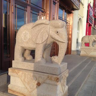 Stone elephants on pedestals flank a wooden doorway.