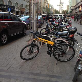 Bicycles and motorcycles are lined up on the footpath.