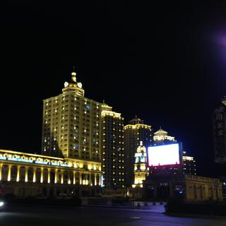Powerful spotlights cast bat shadows on pagoda topped highrises.