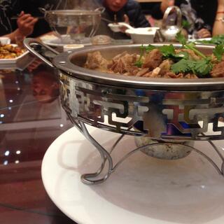 People eat after serving themselves from a heated metal dish filled with meat.