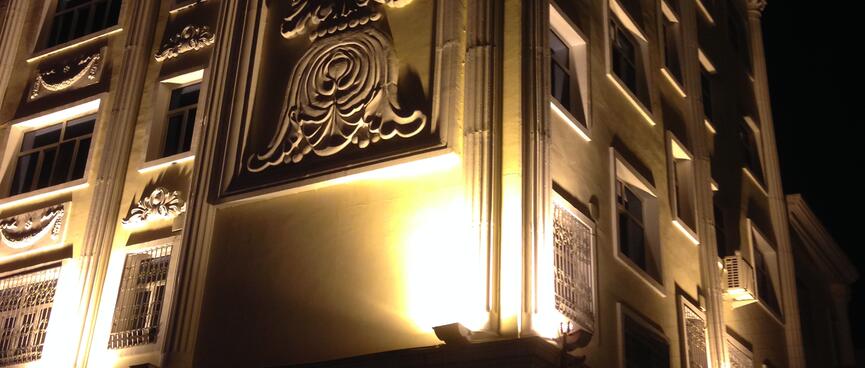 Floodlights highlight window surrounds, but cast windows into darkness.